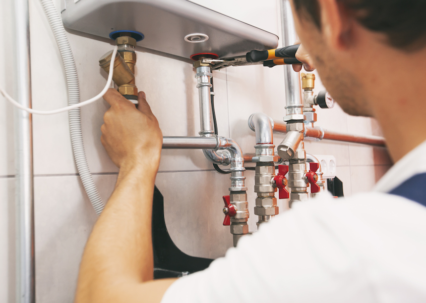 Plumber screwing nut of pipe in the heating system in the boiler room