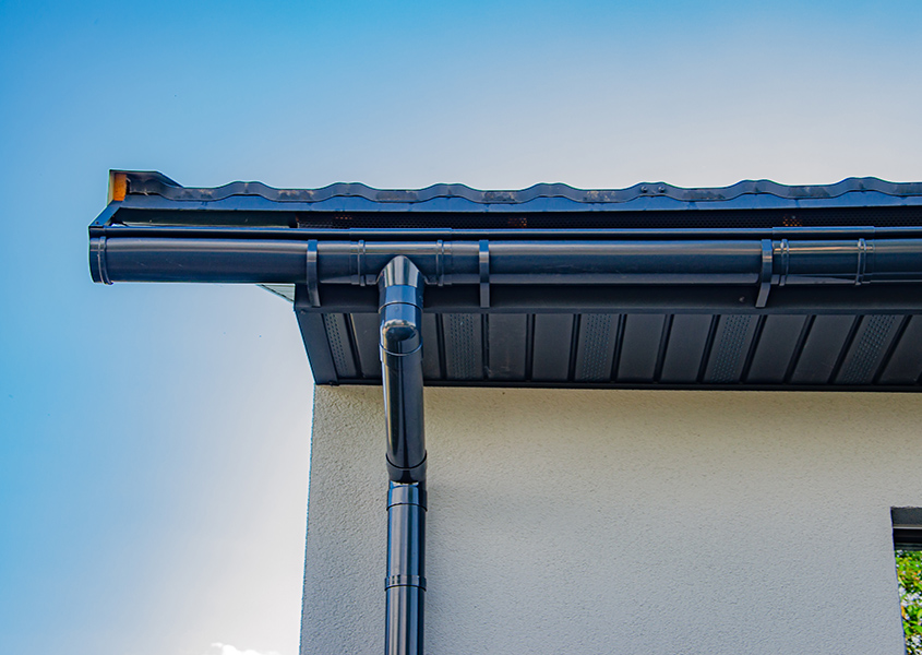 Gutter with downpipe on the roof a house